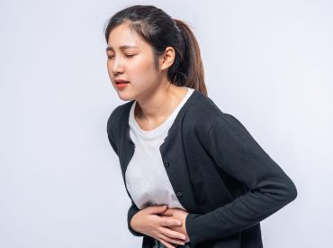 A woman standing with a stomach ache and presses her hand on her PCOD